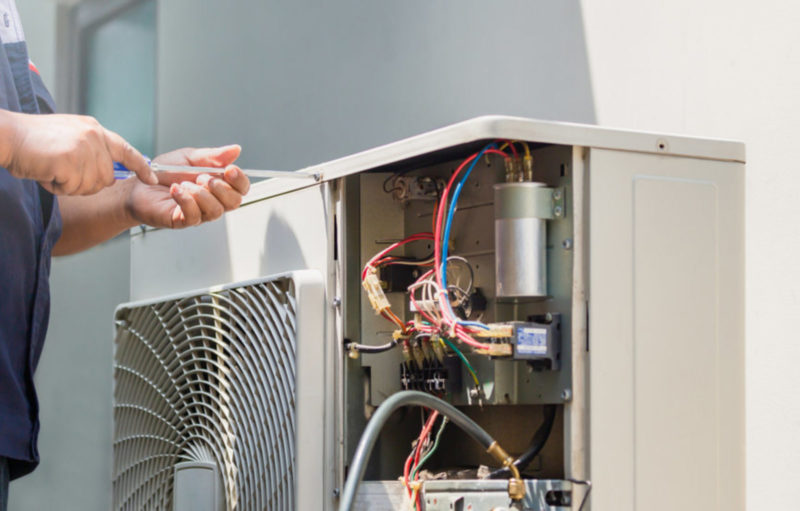 Male technician hands using a screwdriver fixing modern air cond